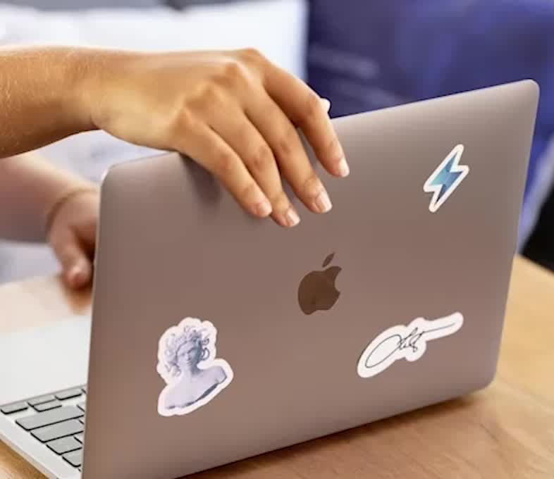 Hands resting on a closed laptop covered in stickers